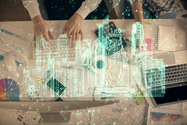 Kadın ve erkeğin birlikte çalıştığı ve binaların hologram çizimlerinin çifte pozlanması. Bilgisayar arkaplanı. Üst Manzara. Akıllı şehir konsepti.