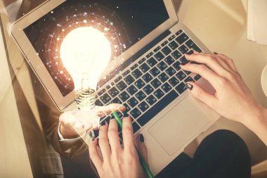 Bilgisayar ve ampul hologramı çizimleri üzerinde çalışan kadın elleri çift pozlama. Üst Manzara. Fikir kavramı.