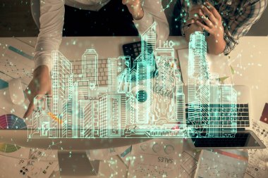 Kadın ve erkeğin birlikte çalıştığı ve binaların hologram çizimlerinin çifte pozlanması. Bilgisayar arkaplanı. Üst Manzara. Akıllı şehir konsepti.