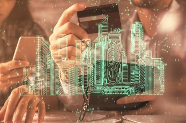 Bir kredi kartı ve kasaba hologramı çizimi tutan kadın ve erkeğin online alışverişine iki kez maruz kalıyorlar. Akıllı şehir konsepti.