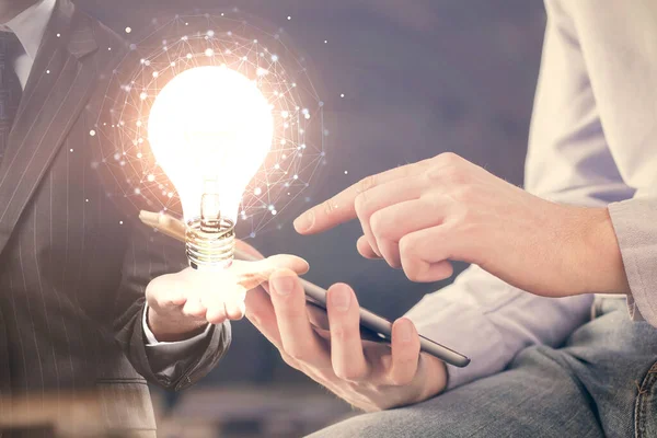 Dijital bir cihaz ve ampul hologram çizimi kullanarak insanın ellerini tutarken çift pozlama. Fikir kavramı.