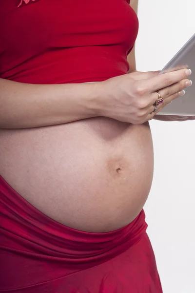 Mulher grávida em vermelho wit tablet pc — Fotografia de Stock