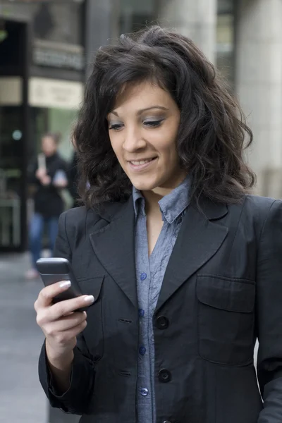 Jeune femme avec smartphone marchant dans la rue — Photo