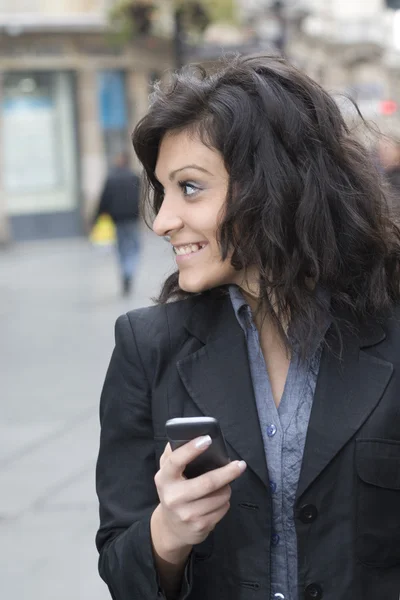 Jeune femme avec smartphone marchant dans la rue — Photo