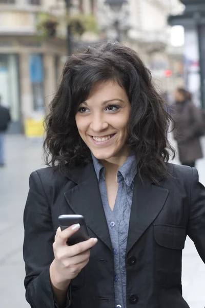 Jeune femme avec smartphone marchant dans la rue — Photo