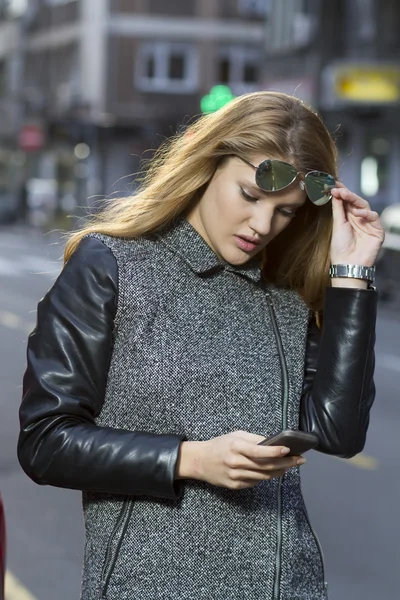 Jonge vrouw met smartphone lopen op straat — Stockfoto