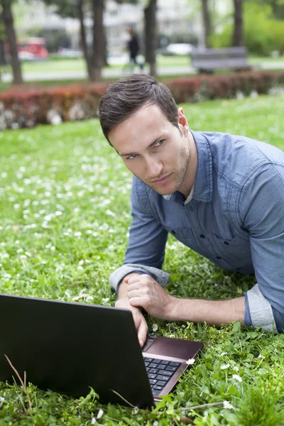 Uomo che utilizza il computer portatile al parco — Foto Stock