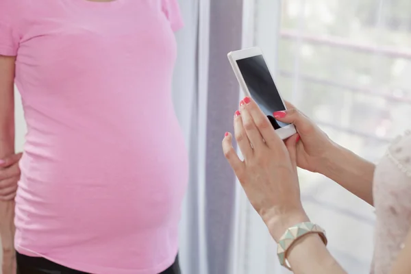 Фотографирование беременных женщин на мобильный телефон — стоковое фото
