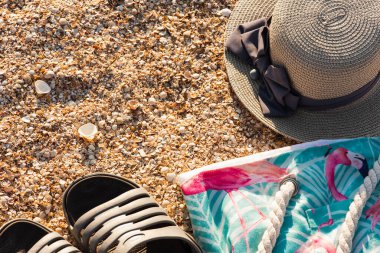 Aksesuar seyahat konsepti: Spor ayakkabıları, kum kumsalında çanta ve hasır şapka, okyanus. Tatil ya da seyahat geçmişi. Uzayı kopyala, düz yat. Yaz ya da sonbahar ülke seyahati kavramı.