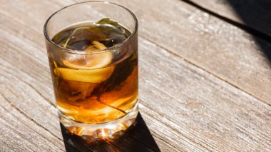 Gri-kahverengi ahşap bir yüzey üzerinde çay, limon ve naneli cam bardak, açık renk gölge, sabah çayının ışığı, üst manzara, ahşap arka planda izole edilmiş. 