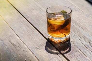 Gri-kahverengi ahşap bir yüzey üzerinde çay, limon ve naneli cam bardak, açık renk gölge, sabah çayının ışığı, üst manzara, ahşap arka planda izole edilmiş. 