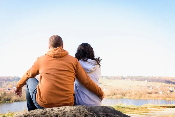 湖の奥にある大きな岩の上で抱き合って座っている若い夫婦が — ストック写真