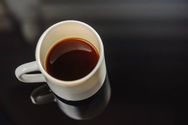 Beyaz seramik bardakta, gri arka planda sade kahve. Yazı için bir yer. Yan görüş, üst görüş. Seçici odak.