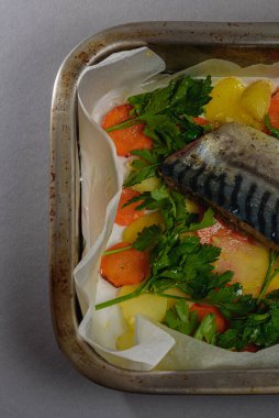 Fırında pişirmeden önce sebzeli, patatesli, havuçlu taze moraine uskumrusu, metal bir şekilde. Sebzeli balık. Gri arkaplan, üst manzara. Ev yemekleri..
