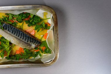 Fırında pişirmeden önce sebzeli, patatesli, havuçlu taze moraine uskumrusu, metal bir şekilde. Sebzeli balık. Gri arkaplan, üst manzara. Ev yemekleri..