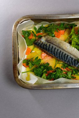 Fırında pişirmeden önce sebzeli, patatesli, havuçlu taze moraine uskumrusu, metal bir şekilde. Sebzeli balık. Gri arkaplan, üst manzara. Ev yemekleri..