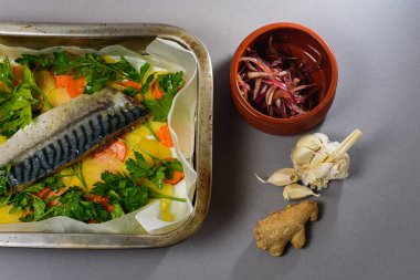 Fırında pişirmeden önce sebzeli, patatesli, havuçlu taze moraine uskumrusu, metal bir şekilde. Sebzeli balık. Gri arkaplan, üst manzara. Ev yemekleri.