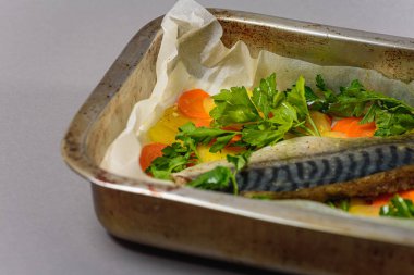 Fırında pişirmeden önce sebzeli, patatesli, havuçlu taze moraine uskumrusu, metal bir şekilde. Sebzeli balık. Gri arkaplan, üst manzara. Ev yemekleri.