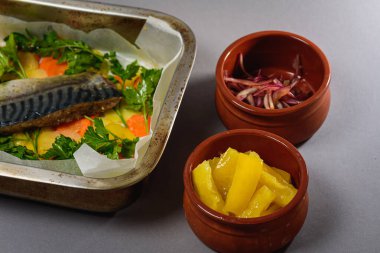 Fırında pişirmeden önce sebzeli, patatesli, havuçlu taze moraine uskumrusu, metal bir şekilde. Sebzeli balık. Gri arkaplan, üst manzara. Ev yemekleri.