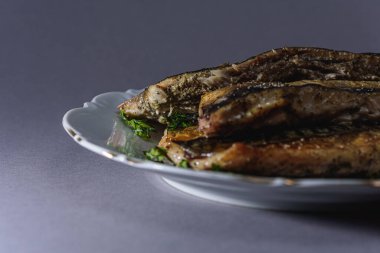 Kısa gövdeli kızarmış uskumru ya da Taylandlı Plato gri arka planda beyaz bir porselen tabakta servis edilir. Tayland 'da popüler balık menüsü. (yakın çekim, yan görünüm) 