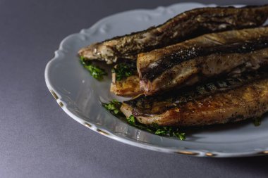 Kısa gövdeli kızarmış uskumru ya da Taylandlı Plato gri arka planda beyaz bir porselen tabakta servis edilir. Tayland 'da popüler balık menüsü. (yakın çekim, yan görünüm) 