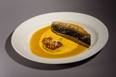 Soslu fırında uskumru balığı, karnabahar ve beyaz bir tabakta sarı püre. Sebzeyle pişirilmiş balık. Gri arka plan. Üst görünüm.