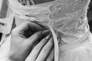 Siyah beyaz fotoğraf. Gelinin arkadaşı gelini düğüne hazırlar, düğmelerini bağlar, elbisesini bağlar gelinin sırtına bir fiyonk takar, gelinin sabah toplantısı. Seçici odak