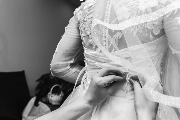 黑白照片 新娘的朋友为新娘的婚礼做准备 帮新娘扣上纽扣 系上衣服 在新娘的背上做一个蝴蝶结 参加新娘的晨会 有选择的重点 — 图库照片