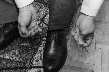 Düğünden önce bağcıkları siyah deri ayakkabılara bağlayan adamın elleri.