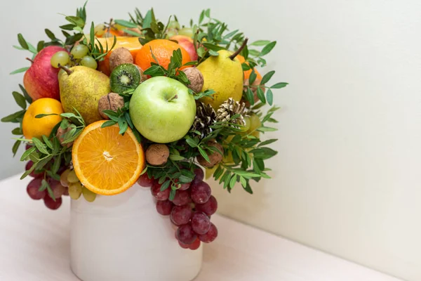 Bouquet of fruits and flowers. Apples, pears, oranges, tangerines, grapes, eucalyptus nuts and cloves.