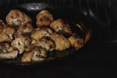 Pişirme, kızartılmış karnabahar ve baharat. Vejetaryen yemekleri, fırında pişirilmiş sağlıklı yiyecekler. Seçici odaklanma. Alçak tuş