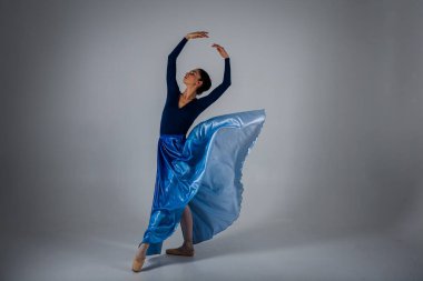 Genç, güzel balerin açık arka planda uzun mavi bir elbiseyle dans ediyor. Bale, dans, dansçı.