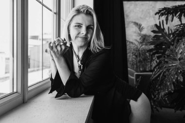 Portrait of a black and white young, pretty European girl emotional in a men's shirt in the bedroom near a large window, smiles, straightens hair. Morning sun, selective focus 