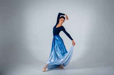 Genç, güzel balerin arka planda uzun bir elbiseyle dans etmek yazıtlara uygun bir yer. Sanat, hareket, ilham konsepti. Sivri ayakkabılı ve elbiseli klasik balerin. Seçici odak