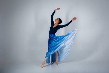 Genç, güzel balerin arka planda uzun bir elbiseyle dans etmek yazıtlara uygun bir yer. Sanat, hareket, ilham konsepti. Sivri ayakkabılı ve elbiseli klasik balerin. Seçici odak