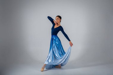 Genç, güzel balerin arka planda uzun bir elbiseyle dans etmek yazıtlara uygun bir yer. Sanat, hareket, ilham konsepti. Sivri ayakkabılı ve elbiseli klasik balerin. Seçici odak