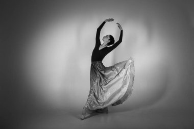 ballerina. A young elegant ballet dancer, dressed in professional attire, shoes and a blue weightless skirt, demonstrates her dancing skills. The beauty of classical ballet. Black and white photo