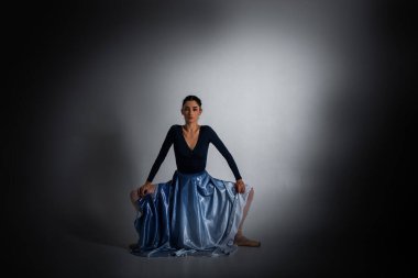ballerina. A young elegant ballet dancer, dressed in professional attire, shoes and a blue weightless skirt, demonstrates her dancing skills. The beauty of classical ballet