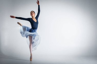 ballerina. A young elegant ballet dancer, dressed in professional attire, shoes and a blue weightless skirt, demonstrates her dancing skills. The beauty of classical ballet