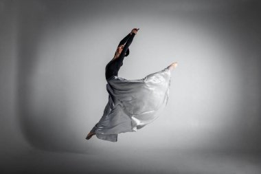 ballerina. A young elegant ballet dancer, dressed in professional attire, shoes and a blue weightless skirt, demonstrates her dancing skills. The beauty of classical ballet. Black and white photo
