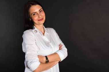 Portre, gülümseyen, çekici, orta yaşlı bir kızın karanlık bir arka planda çekilmiş bir fotoğrafı.