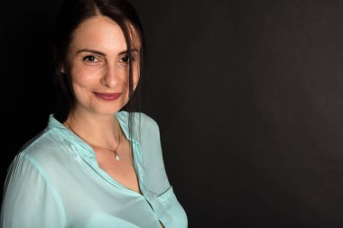 Portre, gülümseyen, çekici, orta yaşlı, dalgalı saçlı, esmer bir kızın stüdyo fotoğrafı..