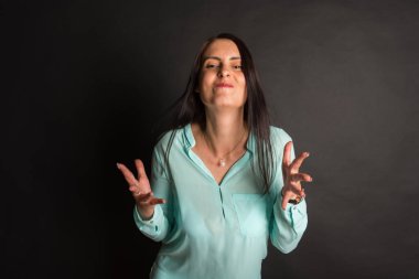 Duygusal meraklı kız, karanlık bir arka planda el hareketlerini gösterir.