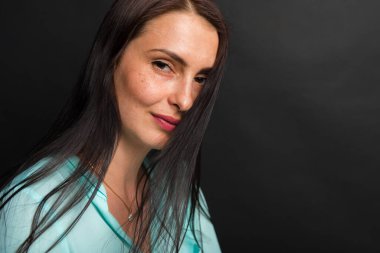 Portre, gülümseyen, çekici, orta yaşlı, dalgalı saçlı, esmer bir kızın stüdyo fotoğrafı..