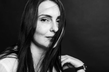 Siyah-beyaz bir portre, stüdyo fotoğrafı, güzel, duygusal oldukça çekici orta yaşlı bir kız koyu bir arka planda.