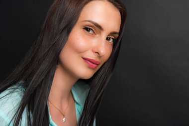 Portre, gülümseyen, çekici, orta yaşlı bir kızın karanlık bir arka planda çekilmiş bir fotoğrafı.