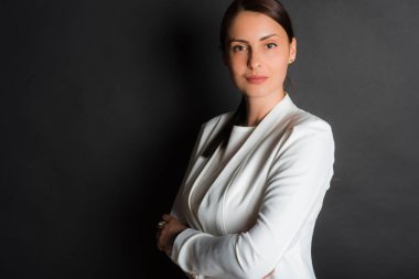 Studio shot of a smiling attractive middle aged woman standing with her arms crossed against a dark background
