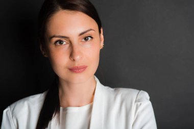 Portre, gülümseyen, çekici, orta yaşlı bir kızın karanlık bir arka planda çekilmiş bir fotoğrafı.