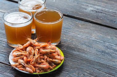 Ahşap zemin üzerinde beyaz bir tabakta taze bira ve fotokopi alanı olan taze karides pişirdim. Sağlıklı deniz ürünleri ve tatil kavramı.