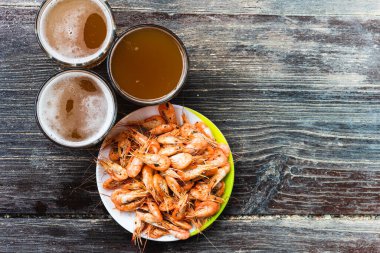 Ahşap zemin üzerinde beyaz bir tabakta taze bira ve fotokopi alanı olan taze karides pişirdim. Sağlıklı deniz ürünleri ve tatil kavramı.